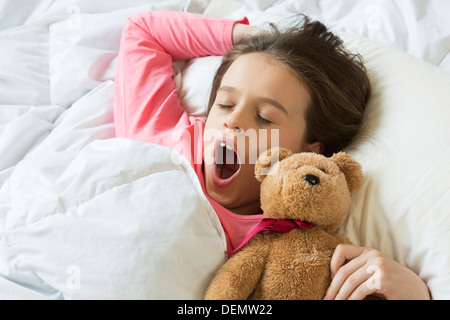 young girl waking up yawning in bed