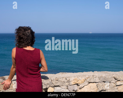 Woman with red dress in front of the sea Stock Photo