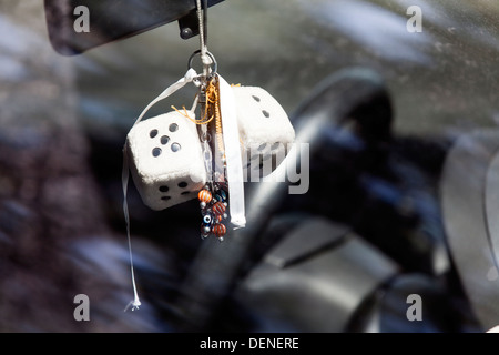 Two furry dice and bead chains hanging from the rear view mirror of a car Stock Photo