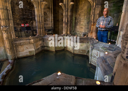 St.Winefride's Well,a holy site where a spring brings water from the hillside for bathing by a devout oriental man.a Wales UK Stock Photo