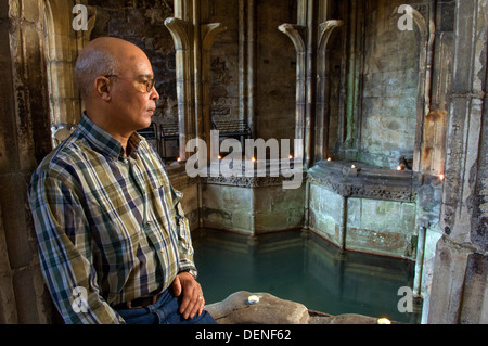 St.Winefride's Well,a holy site where a spring brings water from the hillside for bathing by a devout oriental man.a Wales UK Stock Photo