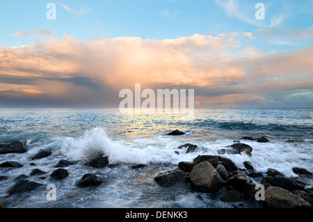 Rocky coast and sea waves at sunset