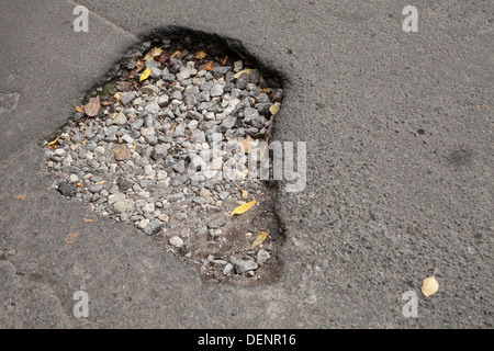 Pothole with gravel on damaged urban asphalt road Stock Photo