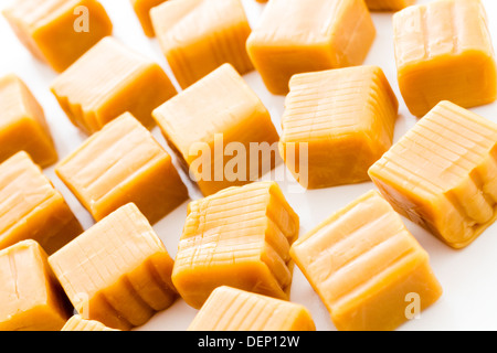 Vanilla caramel candy unwrapped on a white background. Stock Photo