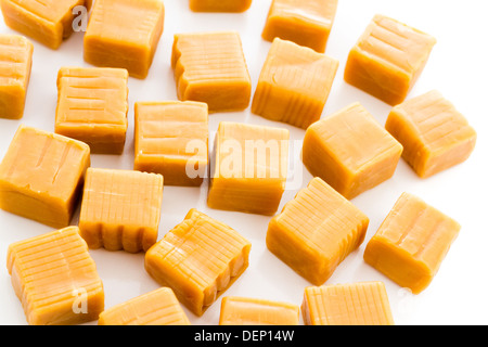 Vanilla caramel candy unwrapped on a white background. Stock Photo