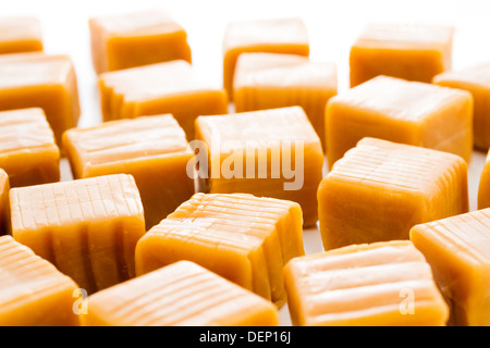 Vanilla caramel candy unwrapped on a white background. Stock Photo