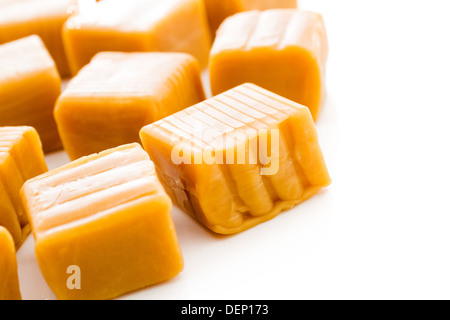 Vanilla caramel candy unwrapped on a white background. Stock Photo