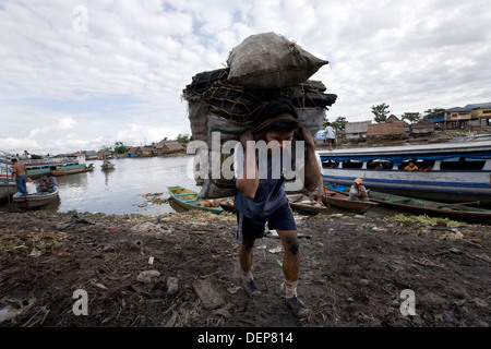 A man carries sacks of coal from one of the boats to the Belen Market. Stock Photo