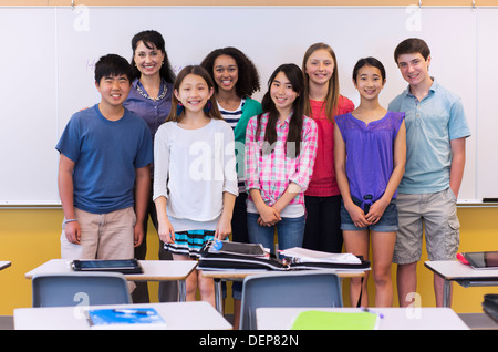 Teacher and students smiling in classroom Stock Photo