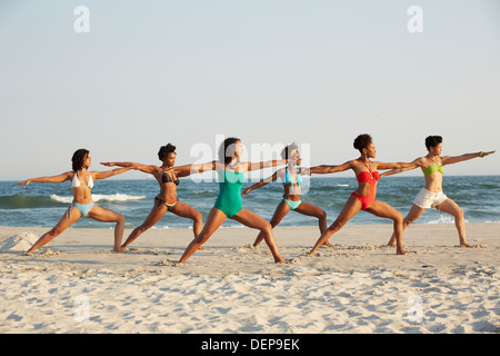 Women practicing yoga on beach Stock Photo