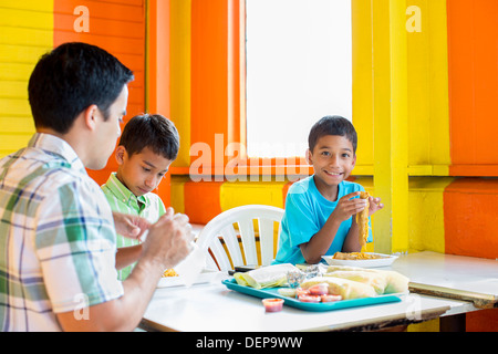 Hispanic boys eating with father in restaurant Stock Photo