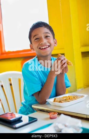 Hispanic boy eating in restaurant Stock Photo