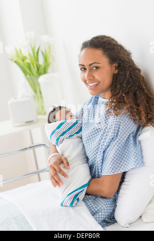 Hispanic mother holding newborn in hospital Stock Photo