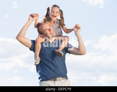 Caucasian father carrying daughter on shoulders