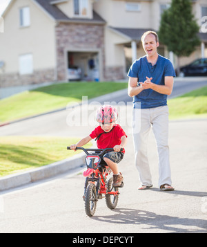 Caucasian father teaching son to ride bicycle Stock Photo