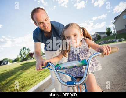 Caucasian father teaching daughter to ride bicycle Stock Photo