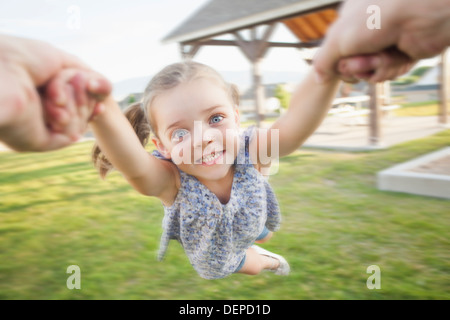 Caucasian father spinning daughter in park Stock Photo