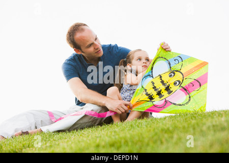 Caucasian father and daughter fixing kite in grass Stock Photo