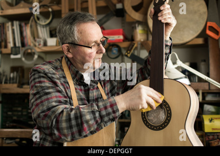 Guitar maker finishing acoustic guitar in workshop Stock Photo