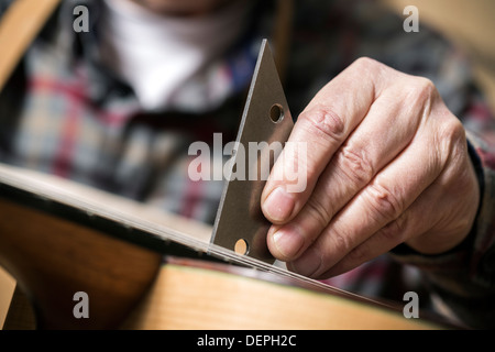 Close up of guitar maker finishing acoustic guitar in workshop Stock Photo