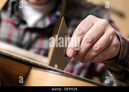 Close up of guitar maker finishing acoustic guitar in workshop Stock Photo