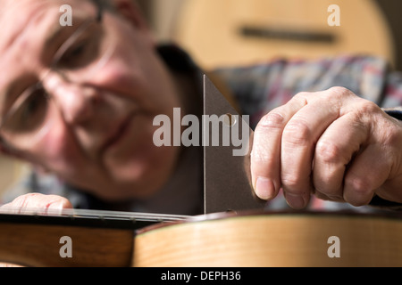 Close up of guitar maker finishing acoustic guitar in workshop Stock Photo