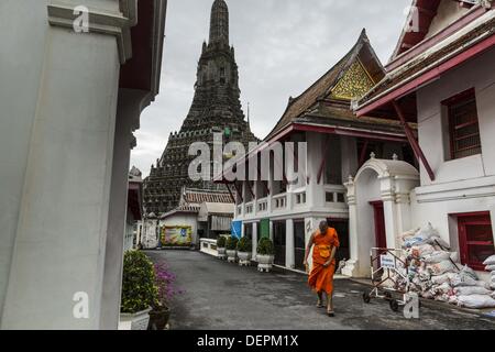 Bangkok, Thailand. 23rd Sep, 2013. A Buddhist monk walks out from the monk housing area to the main prayer hall at Wat Arun in Bangkok. The famous central prang of the temple is in the background. The full name of the temple is Wat Arunratchawararam Ratchaworamahavihara. The outstanding feature of Wat Arun is its central prang (Khmer-style tower). The world-famous stupa, known locally as Phra Prang Wat Arun, will be closed for three years to undergo repairs and renovation along with other structures in the temple compound. This will be the biggest repair and renovation work on the stupa in t Stock Photo