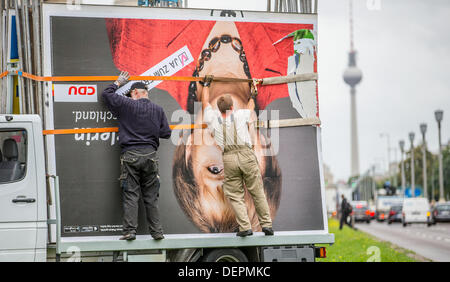 Berlin, Germany. 23rd Sep, 2013. Workers fix an election poster picturing Angela Merkel on a truck with the TV tower in the background in Berlin, Germany, 23 September 2013. Photo: HANNIBAL HANSCHKE/dpa/Alamy Live News Stock Photo