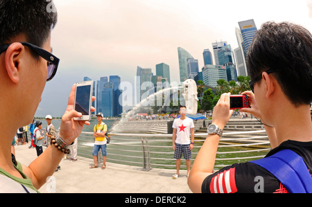 Tourists pose before Singapore landmark statue Tourists pose before the  Merlion statue against the