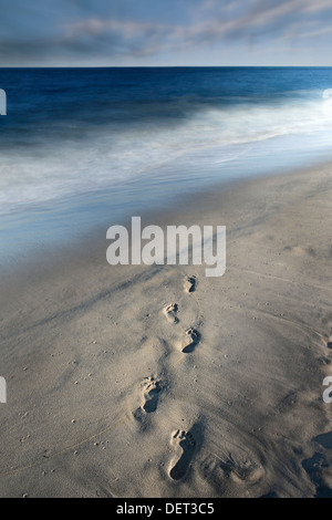 Footprints In Sand And Blurry Ocean Waves With Moving Clouds Stock Photo