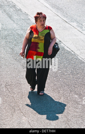 Obese woman (from above) walking along street + shadow - France. Stock Photo