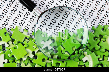 puzzles and magnifying glass on a binary code Stock Photo