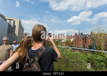 Young couple taking a photograph with their smartphone while visiting The High Line Park in NYC Stock Photo