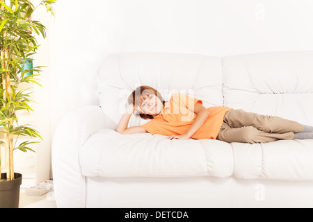 One happy smiling relaxed boy 10 years old laying on the sofa at home coach Stock Photo