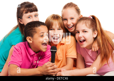 Close-up of a group of happy exited diversity looking kids, boys and girls, singing together sitting on the coach in living room Stock Photo