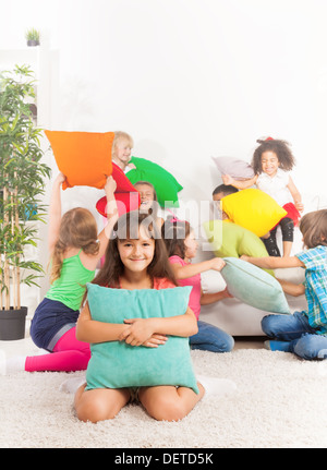 Pillow fight - on happy little Caucasian girl with pillow and her friends fighting on background  Stock Photo