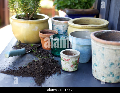 Many empty terracotta plant pots on the counter with soil and trowel Stock Photo