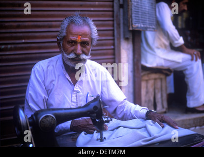 Indian man (tailor) working on sewing machine in the streets of Jaipur, Rajasthan, India. Stock Photo