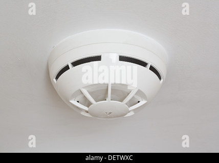 ceiling mounted white fire detector used to activate warning systems in residential buildings Stock Photo