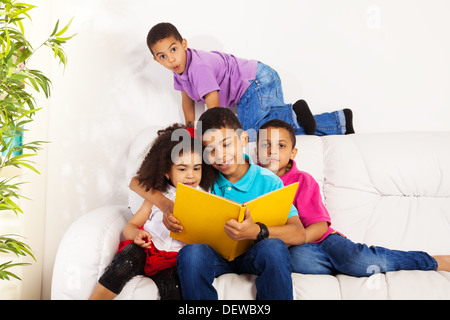 Family, group of four kids with older brother reading books to brothers and sister Stock Photo