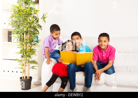 Family, group of four kids with older brother reading books to younger brothers and sister Stock Photo