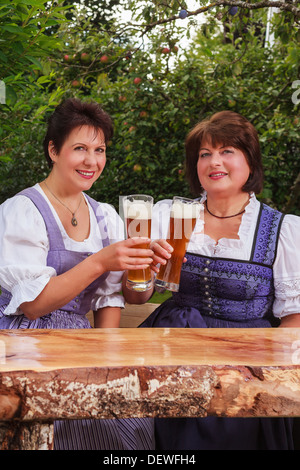 Happy women in dirndls toasting with beer Stock Photo