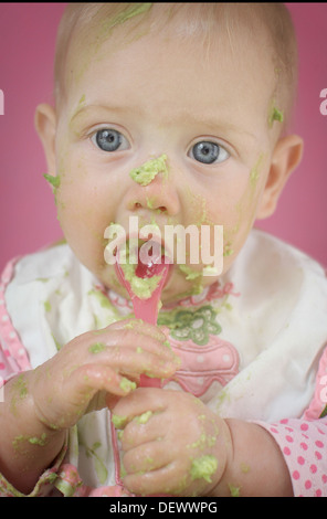 Baby eating avocado in high chair, weaning photo Stock Photo