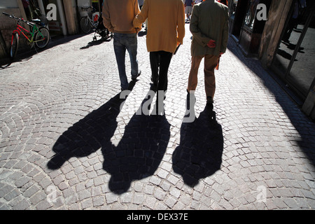 The shadows of three elderly men walking down a cobbled street in Sulmona, Italy. Stock Photo