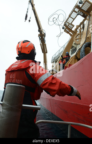 Petty Officer 2nd Class Jerry Speicher, a boatswain's mate aboard the Coast Guard Cutter Healy, throws a smallboat line to Petty Officer 1st Class Kenneth Cook, also a boatswain's mate aboard the Healy, during operations in the Arctic Ocean, Sept. 12, 201 Stock Photo