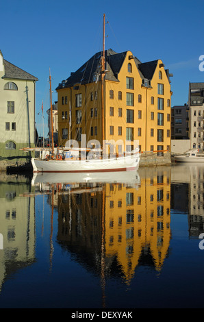 Yellow house and a sailing boat reflected in the calm water of the inner harbor of Ålesund, Alesund, Moere og Romsdal, Norway Stock Photo