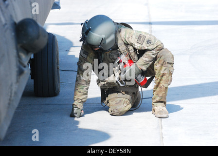 Pfc. Zach Fike, a CH-47 Chinook helicopter crew chief assigned to B Company, 2nd Battalion (General Support), 149th Aviation Regiment (Texas/Oklahoma National Guard), serving under the 10th Combat Aviation Brigade, inspects the hooks used to carry externa Stock Photo