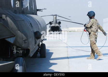 Pfc. Zach Fike, a CH-47 Chinook helicopter crew chief assigned to B Company, 2nd Battalion (General Support), 149th Aviation Regiment (Texas/Oklahoma National Guard), serving under the 10th Combat Aviation Brigade, communicates with the aircraft crew duri Stock Photo