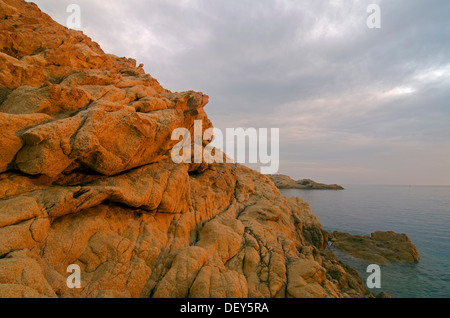 The red granite rocks of the island Ile de la Pietra near L'Île-Rousse illuminated by the first light of the day. L'Île-Rousse Stock Photo
