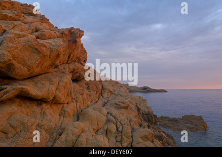 The red granite rocks of the island Ile de la Pietra near L'Île-Rousse illuminated by the first light of the day. L'Île-Rousse Stock Photo